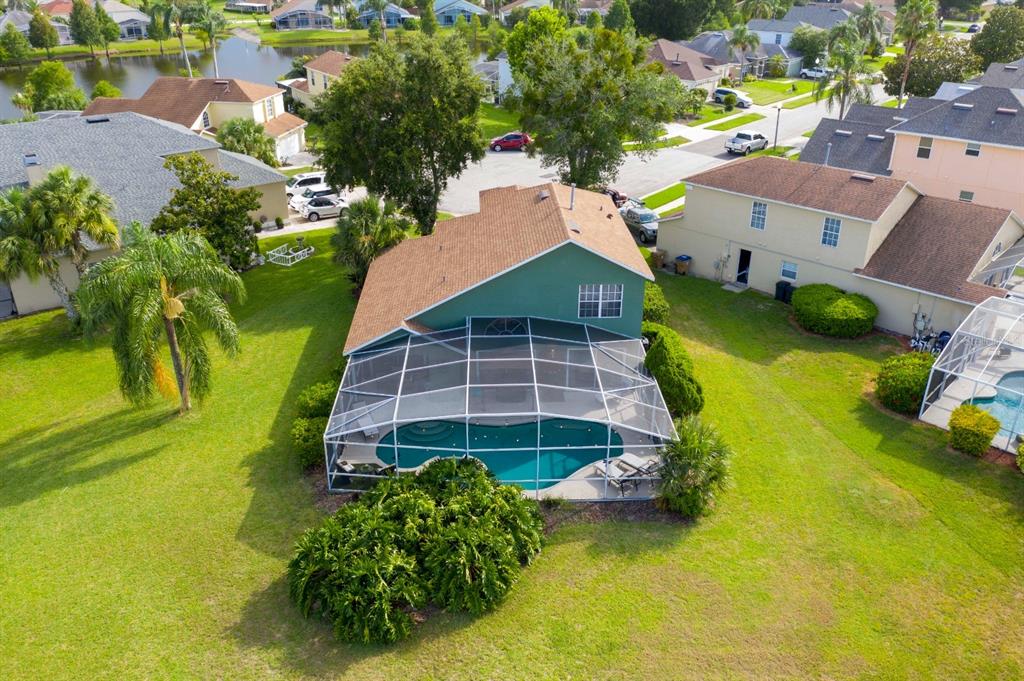An aerial view of a green house with a screened-in pool and backyard — 8051 WHITE CRANE COURT, KISSIMMEE, FL