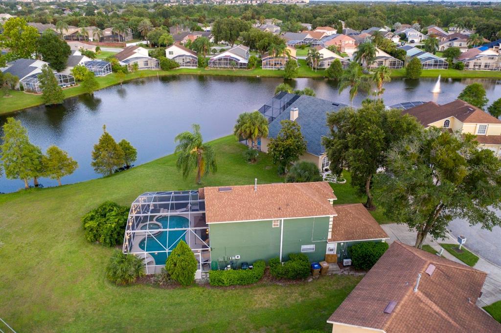 An aerial view of a green house with a screened pool overlooking a community lake — 8051 WHITE CRANE COURT, KISSIMMEE, FL