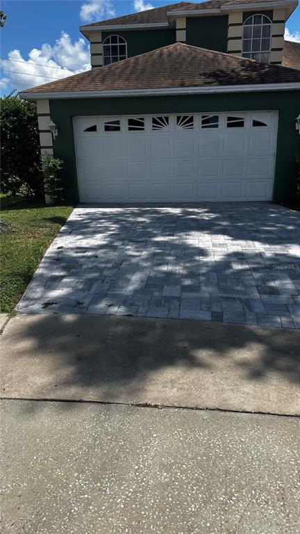 A two-story house features a white garage door and a gray paver driveway — 8051 WHITE CRANE COURT, KISSIMMEE, FL