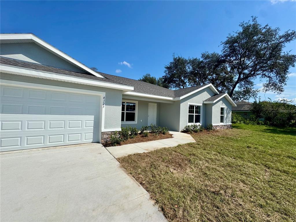 A light-colored single-story house features a two-car garage, a concrete driveway, and a front walkway — 7238 SW 125TH TERRACE ROAD, OCALA, FL