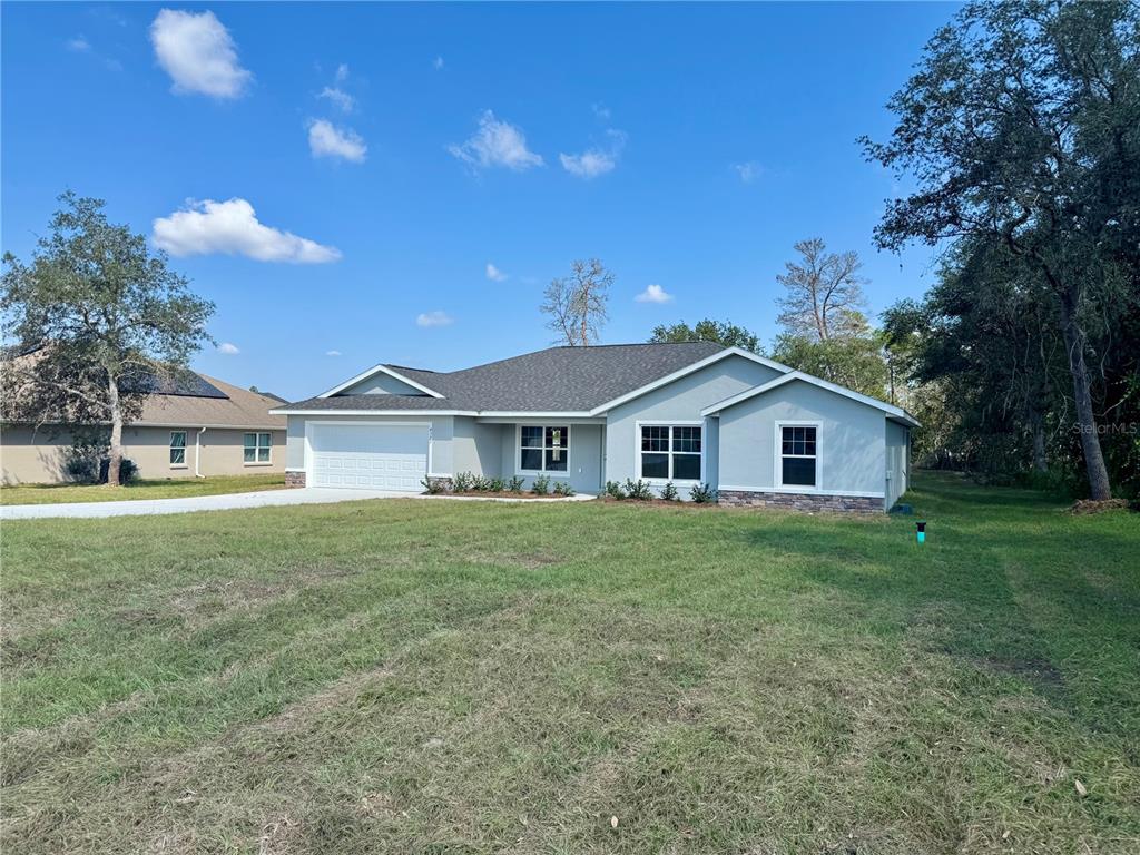 A single-story house with a light gray exterior, stone accents, and a two-car garage — 7238 SW 125TH TERRACE ROAD, OCALA, FL