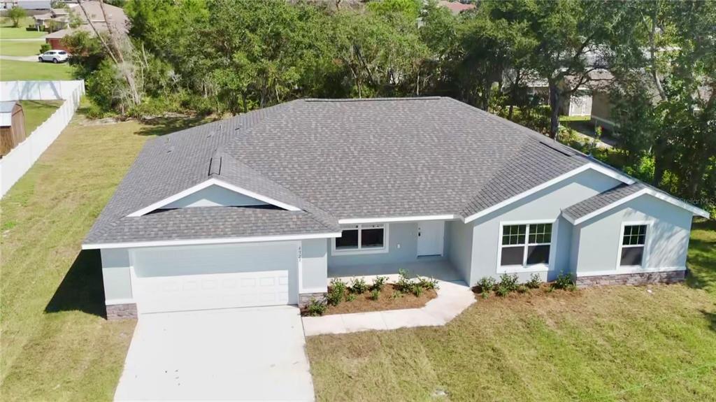 An aerial view of a single-story house with a gray roof, light exterior, and driveway — 7238 SW 125TH TERRACE ROAD, OCALA, FL