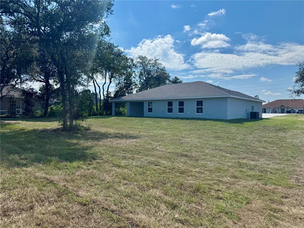The exterior of a light-colored house with a large backyard and mature trees — 7238 SW 125TH TERRACE ROAD, OCALA, FL