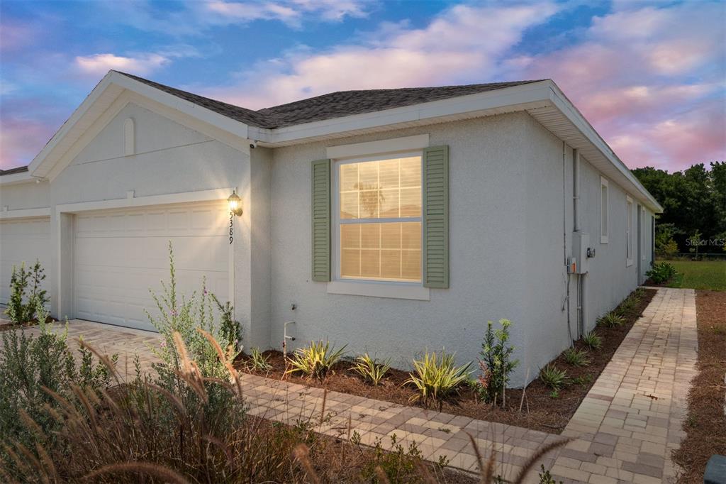 A single-story house with a white stucco exterior, a garage, and a paved walkway — 5389 NW 48TH PLACE, OCALA, FL