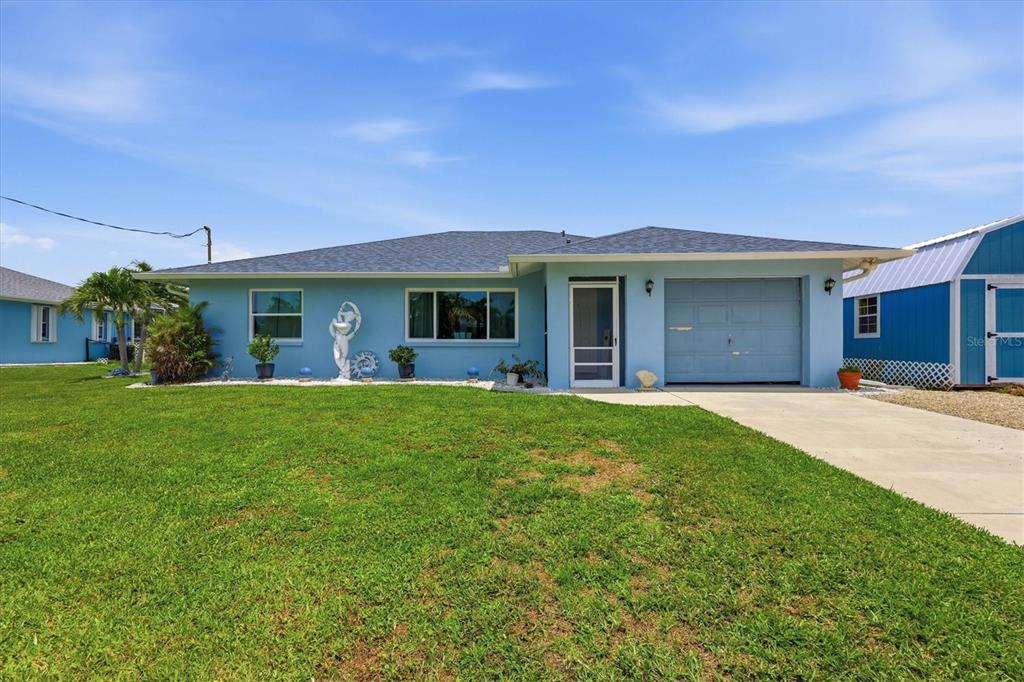A light blue single-story house with a garage and a front lawn under a blue sky — 3514 BLITMAN STREET, PORT CHARLOTTE, FL