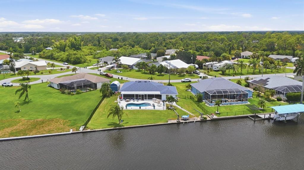 An aerial view shows waterfront houses with swimming pools and boat docks in a residential neighborhood — 3514 BLITMAN STREET, PORT CHARLOTTE, FL