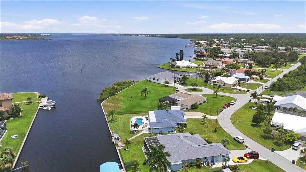 An aerial view shows waterfront houses with swimming pools along a canal leading to a bay — 3514 BLITMAN STREET, PORT CHARLOTTE, FL