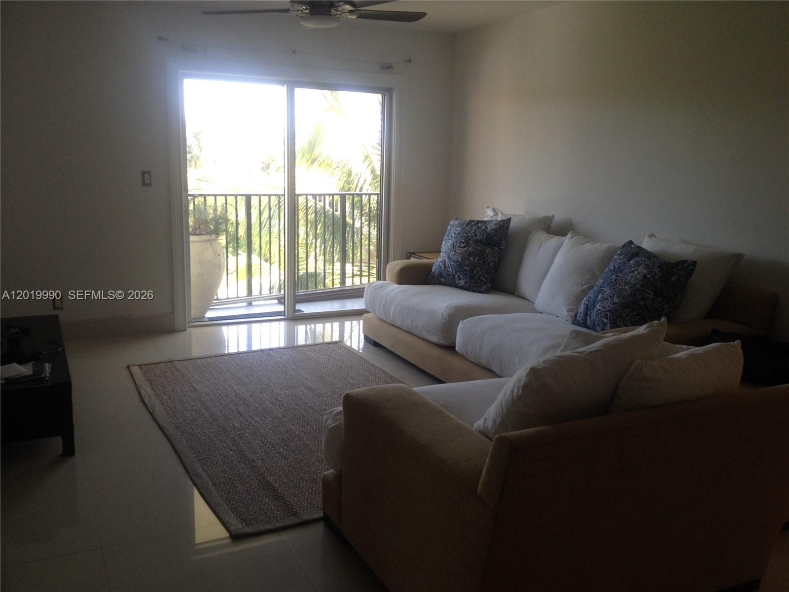A living room features a beige sectional sofa, a textured area rug, and a sliding door — 6855 Edgewater Dr, Coral Gables FL 33133, CORAL GABLES, FL