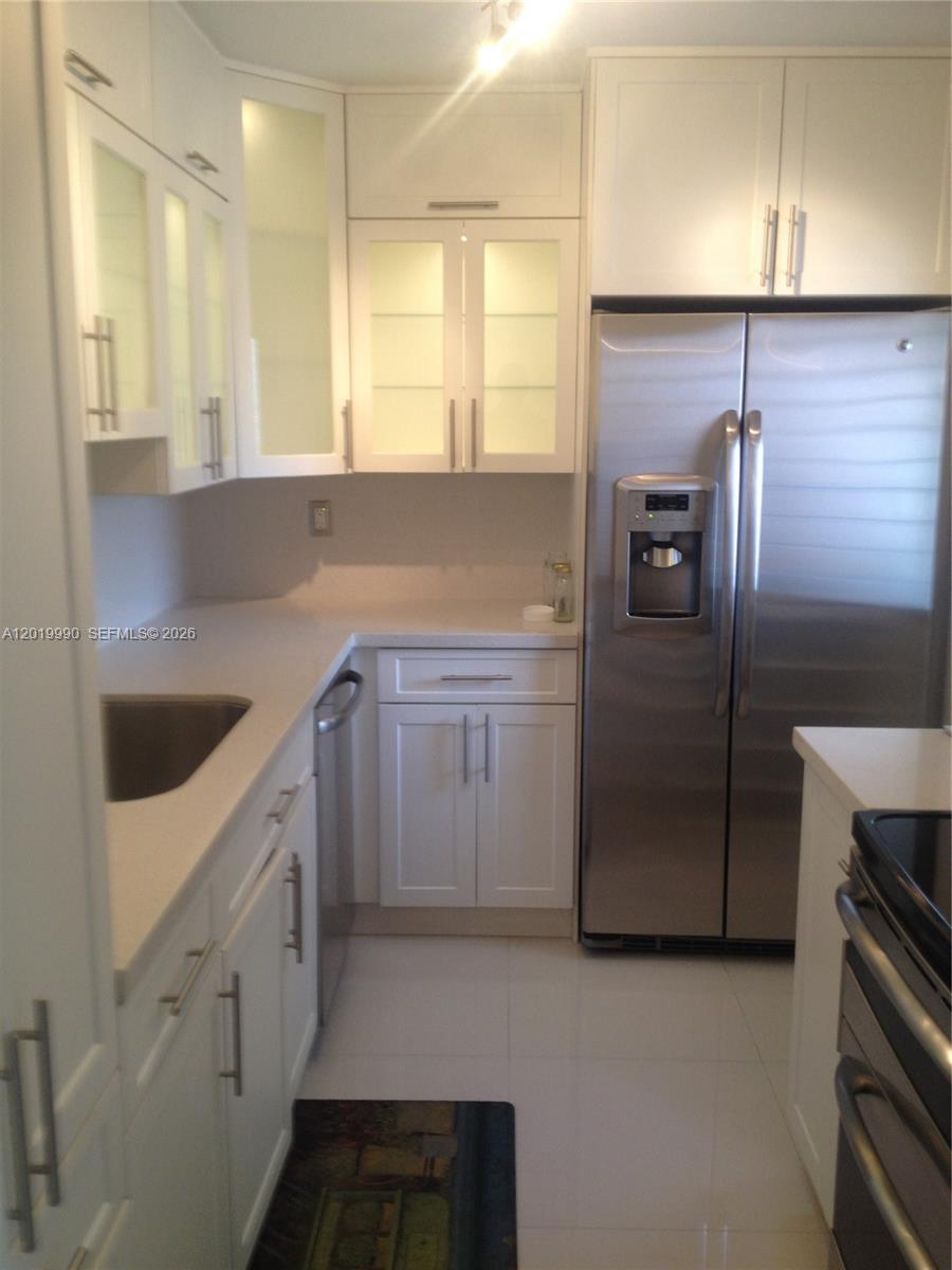 A kitchen features white cabinets, stainless steel appliances, and light-colored countertops — 6855 Edgewater Dr, Coral Gables FL 33133, CORAL GABLES, FL