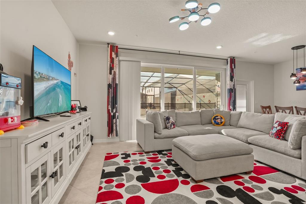 A living room features a large sectional sofa, a patterned area rug, and a television — 1284 BLUE ISLAND DRIVE, CLERMONT, FL