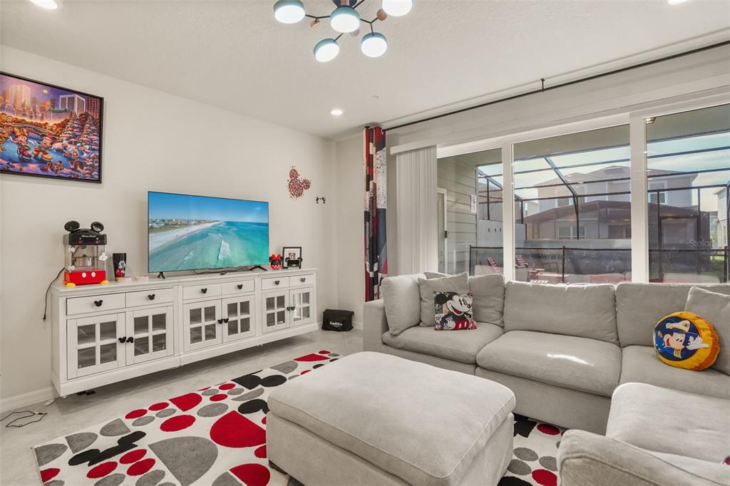 A living room features a white media console, a sectional sofa, and Mickey Mouse-themed decor — 1284 BLUE ISLAND DRIVE, CLERMONT, FL