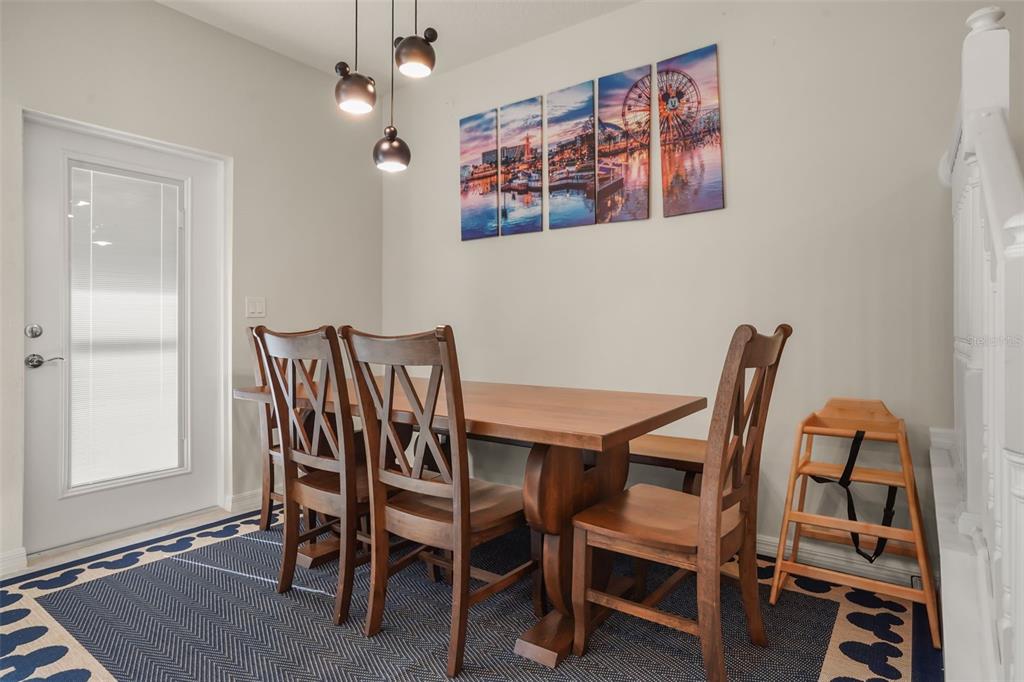 A dining room features a wooden table, four chairs, a high chair, and wall art — 1284 BLUE ISLAND DRIVE, CLERMONT, FL