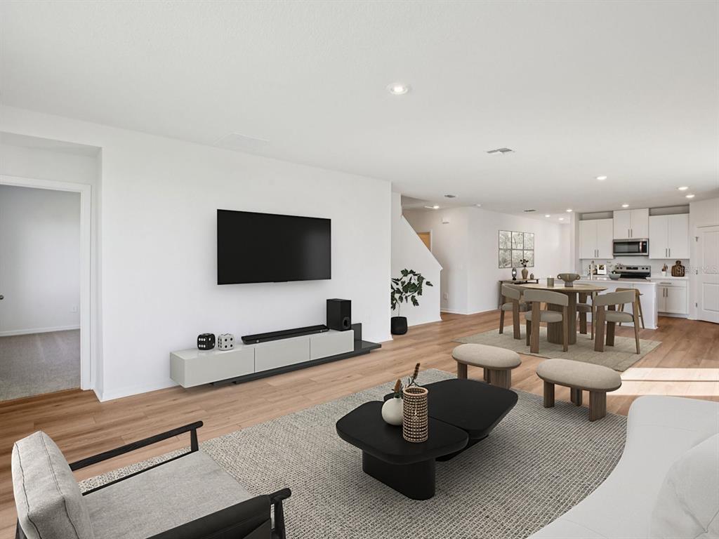 A bright, open-concept living and dining area features light wood flooring and white walls — 7176 RAY CREEK DRIVE, BROOKSVILLE, FL