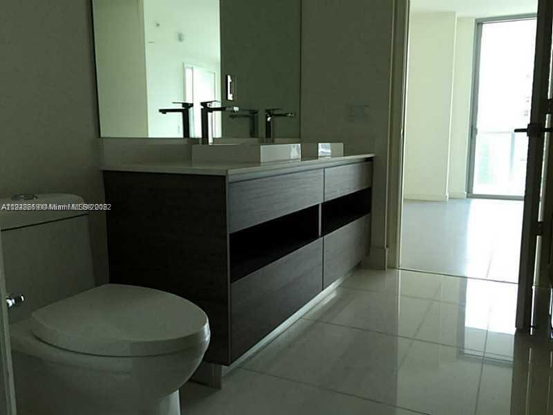 A modern bathroom features a dark wood double vanity, white sinks, and a white toilet — 1100 S MIAMI AVE # 2903, Miami FL 33130, MIAMI, FL