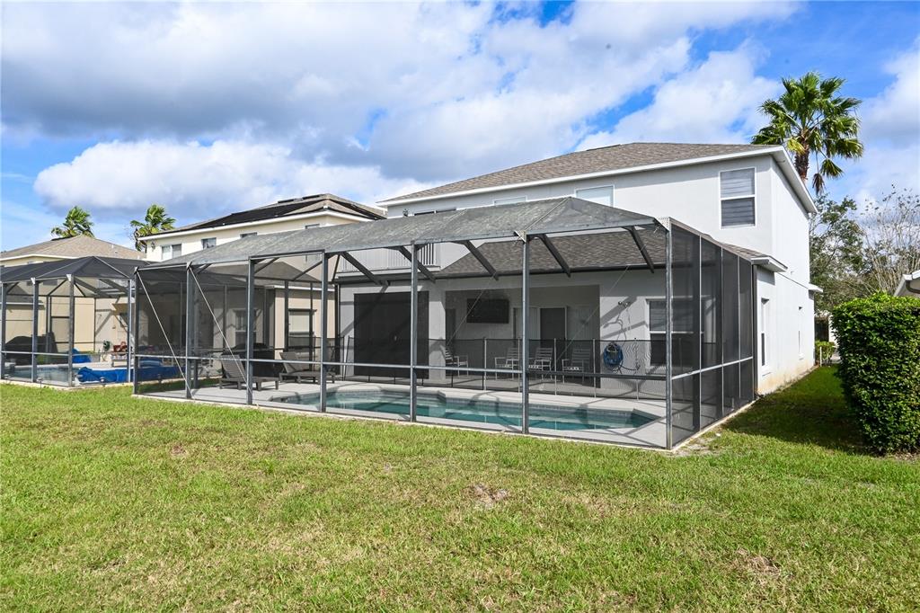 A two-story house features a screened-in pool enclosure and a grassy backyard — 4733 CUMBRIAM LAKES DRIVE, KISSIMMEE, FL