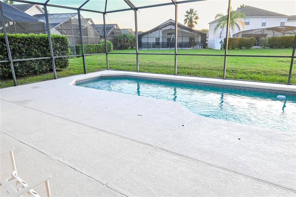 A screened-in patio features a swimming pool and a view of a grassy backyard — 4733 CUMBRIAM LAKES DRIVE, KISSIMMEE, FL
