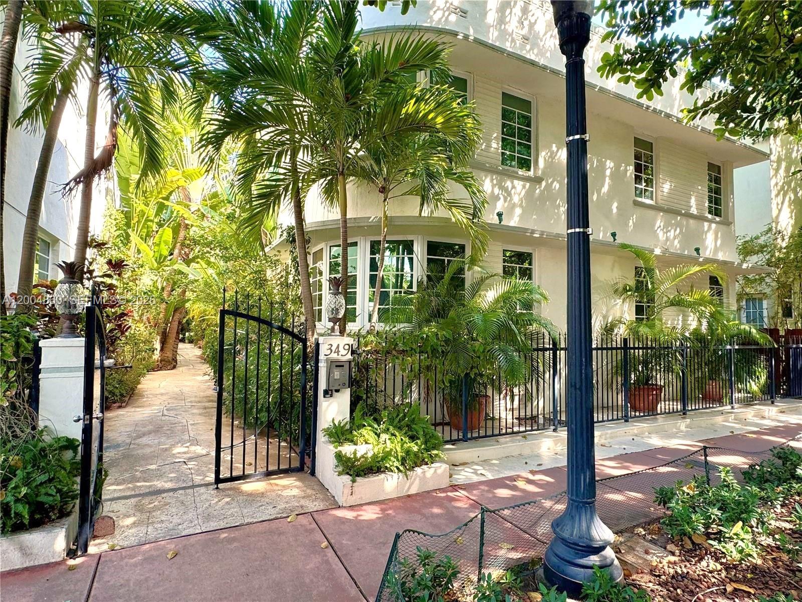 A white two-story building with a gated entrance and lush tropical landscaping — 349 Meridian Ave # B202, Miami Beach FL 33139, MIAMI BEACH, FL