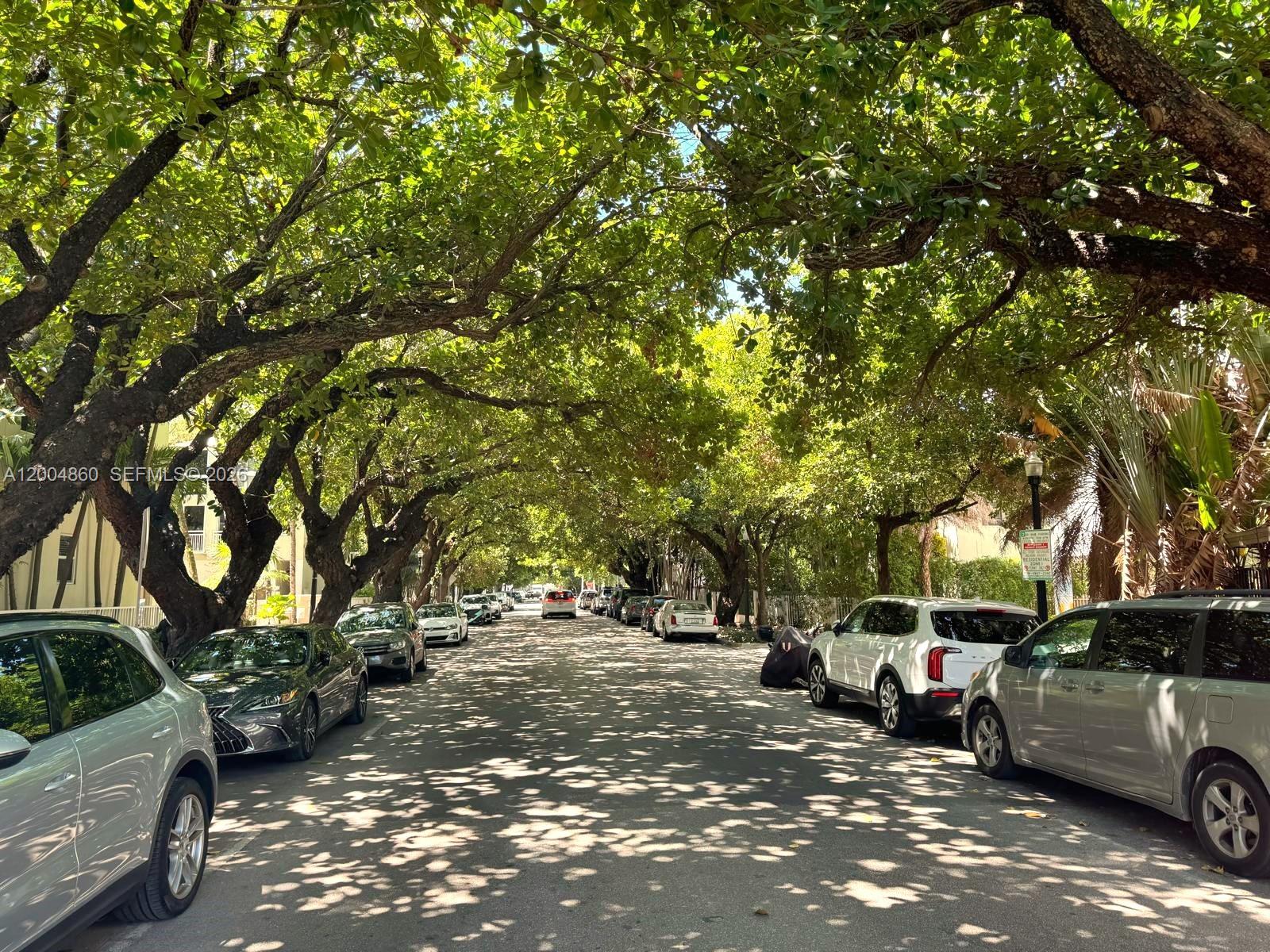 A tree-lined residential street features parked cars along both sides of the road — 349 Meridian Ave # B202, Miami Beach FL 33139, MIAMI BEACH, FL
