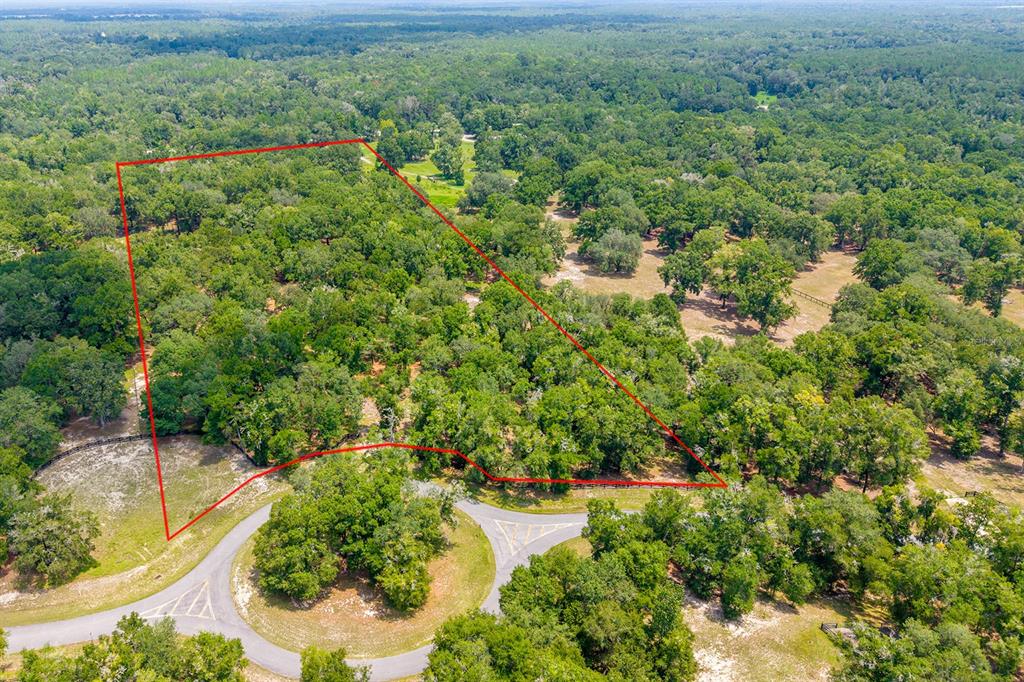 An aerial view shows a wooded plot of land outlined in red near a road — 4316 NE 27TH LANE, HIGH SPRINGS, FL