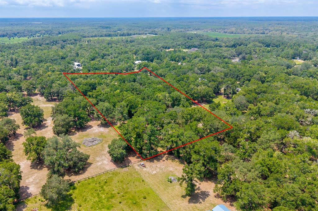 An aerial view shows a wooded lot outlined in red within a rural landscape — 4316 NE 27TH LANE, HIGH SPRINGS, FL