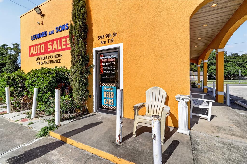 The exterior of a yellow commercial building features a glass door and a plastic chair — 595 9TH STREET UNIT 115, WINTER GARDEN, FL