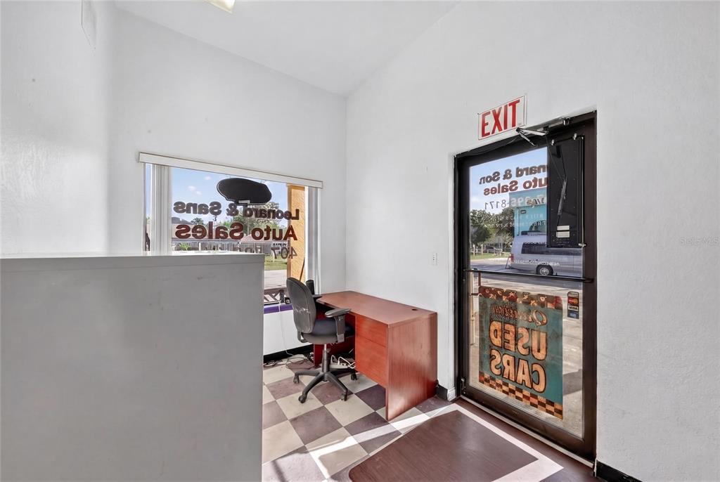 An office space features a desk, a rolling chair, a checkered floor, and a glass door — 595 9TH STREET UNIT 115, WINTER GARDEN, FL