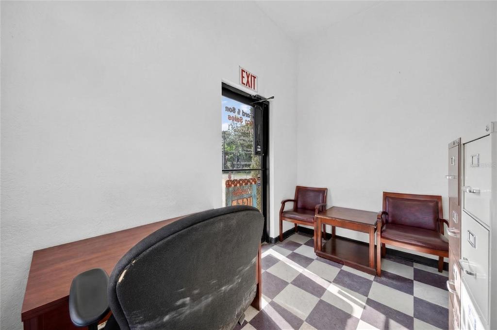 An office space features a desk, two chairs, a side table, and checkered flooring — 595 9TH STREET UNIT 115, WINTER GARDEN, FL