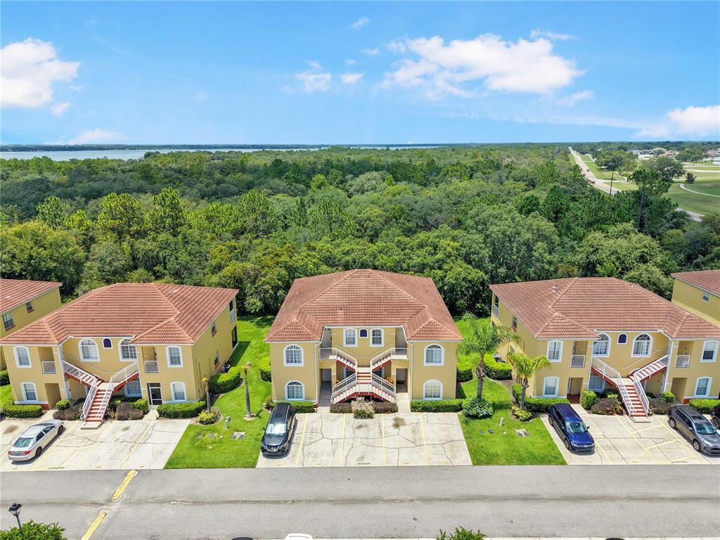 An aerial view shows three multi-story apartment buildings with tile roofs and parking spaces — 12201 INDIAN CREEK DRIVE, POINCIANA, FL
