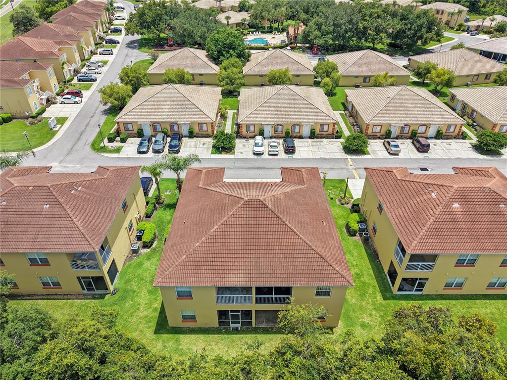An aerial view shows multiple multi-story apartment buildings with tile roofs and surrounding green lawns — 12201 INDIAN CREEK DRIVE, POINCIANA, FL