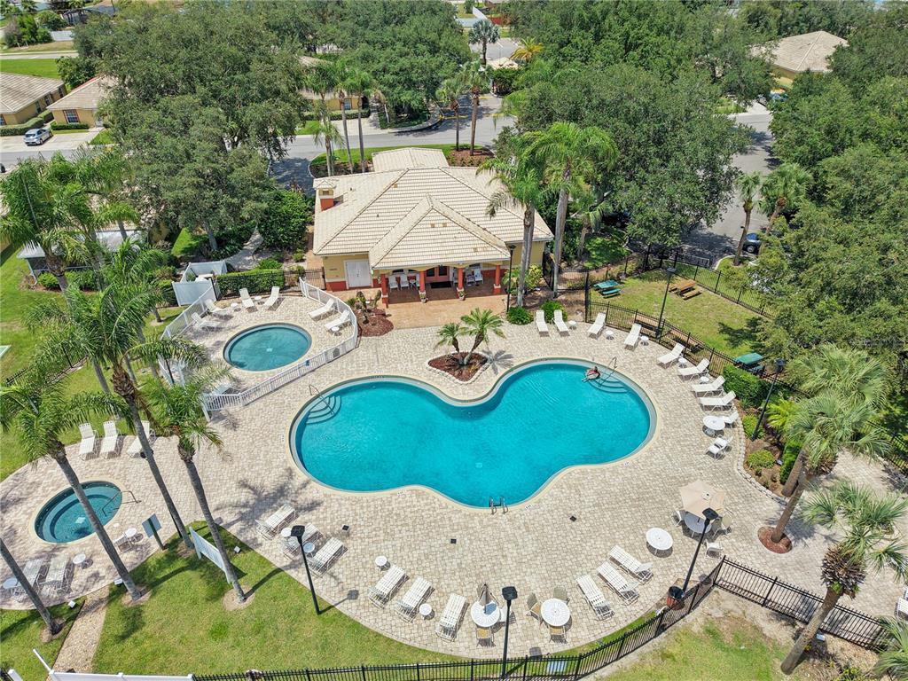 An aerial view shows a community swimming pool and hot tub with lounge chairs — 12201 INDIAN CREEK DRIVE, POINCIANA, FL