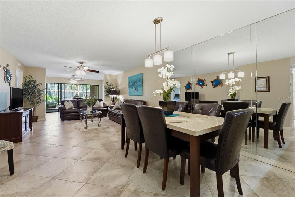 A dining area with a stone table and dark chairs sits before a mirrored wall — 5501 ASHTON WAY UNIT 5501, SARASOTA, FL