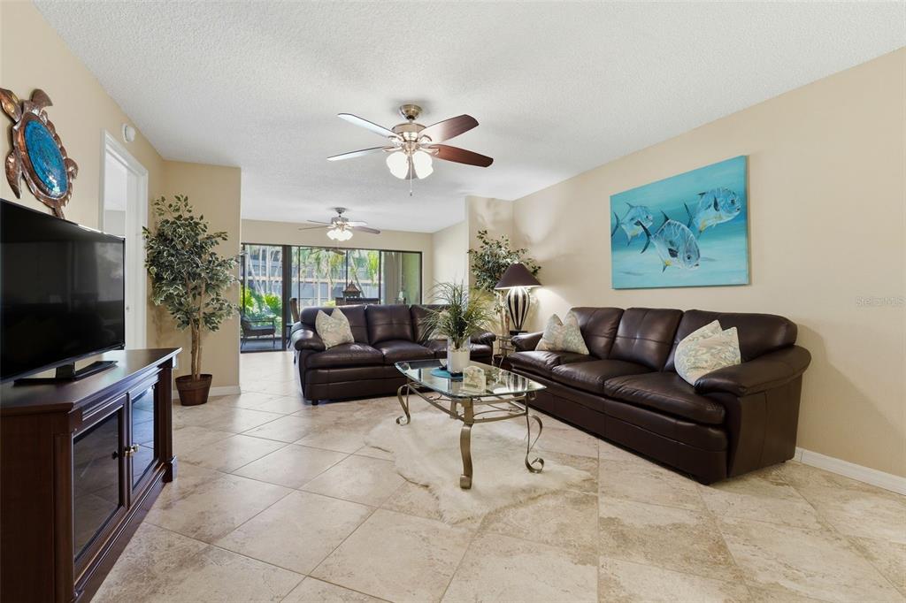 A living room features tile flooring, two dark leather sofas, and a coastal-themed painting — 5501 ASHTON WAY UNIT 5501, SARASOTA, FL