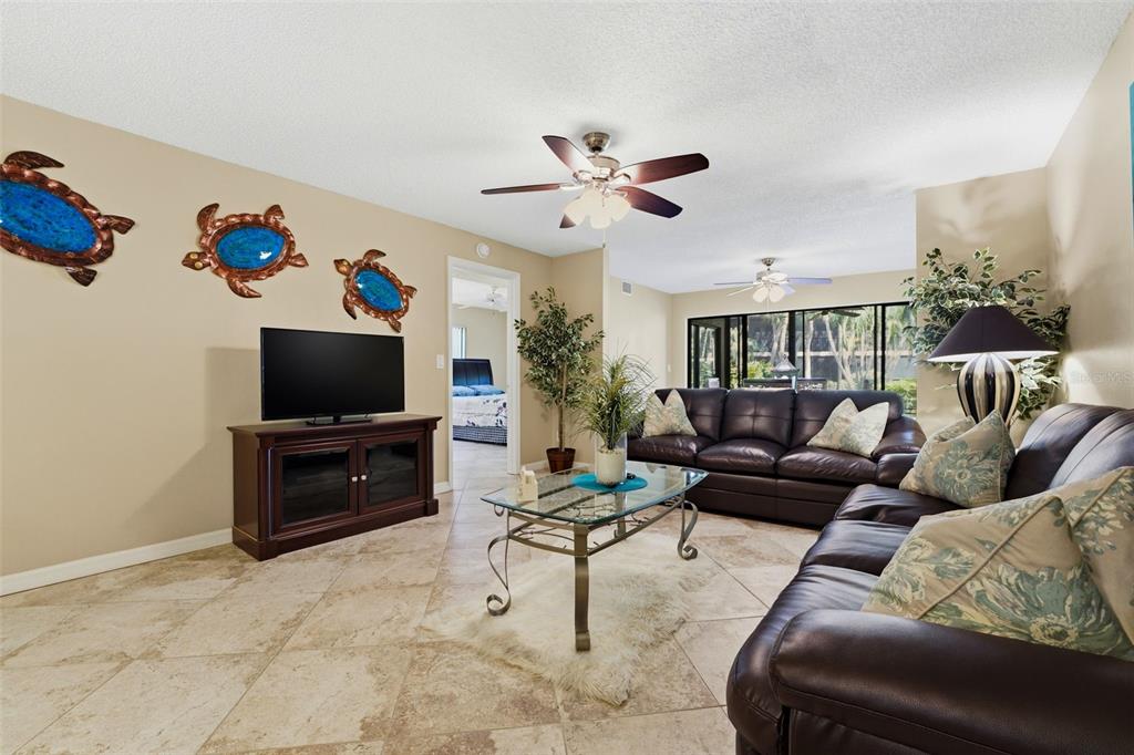 A living room features tile flooring, a dark leather sofa, a glass coffee table, and wall-mounted turtles — 5501 ASHTON WAY UNIT 5501, SARASOTA, FL