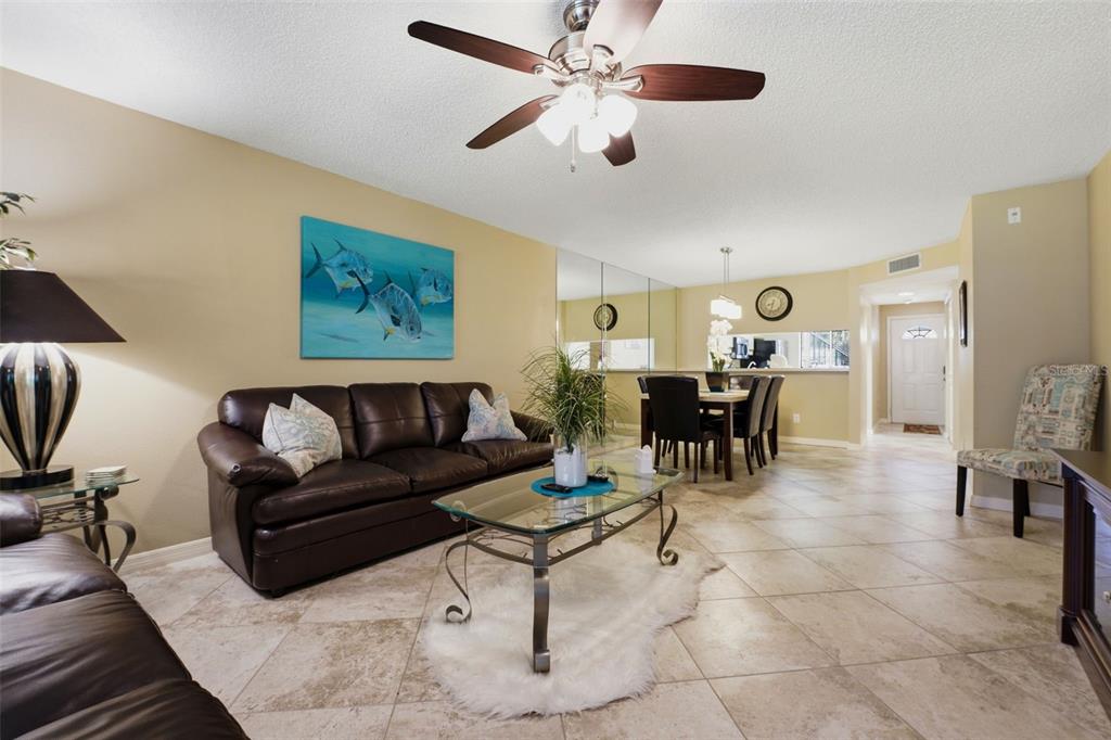 A living room with tile floors, a brown leather sofa, and a glass coffee table — 5501 ASHTON WAY UNIT 5501, SARASOTA, FL