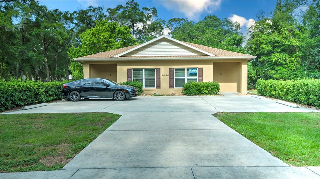 A single-story duplex with a concrete parking area and a black sedan parked outside — 1404 NW 18TH AVENUE, OCALA, FL