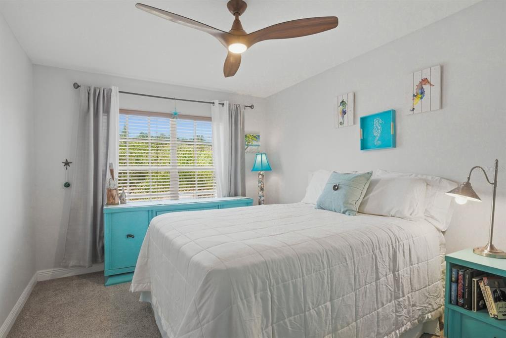 A bedroom features a white bed, a turquoise dresser, a ceiling fan, and coastal-themed decor — 208 VALENCIA CIRCLE, ST PETERSBURG, FL
