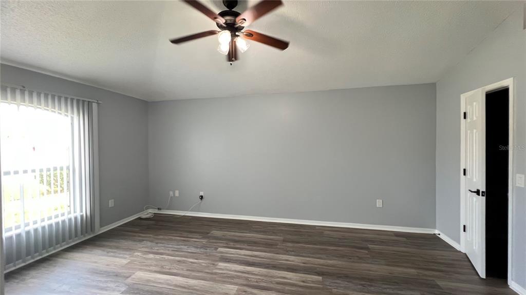 An empty room with gray walls, wood-look flooring, a ceiling fan, and a window — 485 MARTIGUES DRIVE, KISSIMMEE, FL
