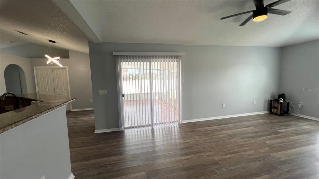 A living room with gray walls, wood-look flooring, a ceiling fan, and sliding glass doors — 485 MARTIGUES DRIVE, KISSIMMEE, FL
