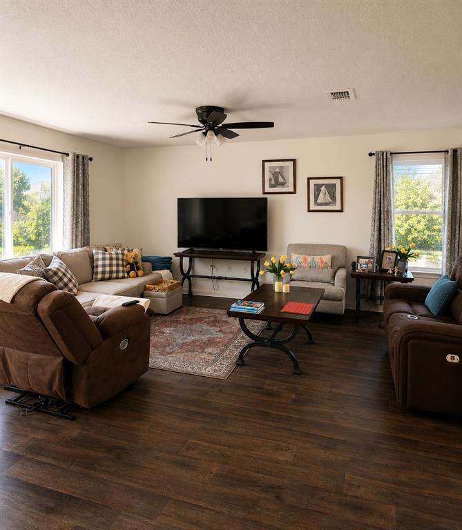 A living room features brown reclining furniture, a television on a stand, and wood flooring — 5418 HOLLOW BIRCH DRIVE, JACKSONVILLE, FL