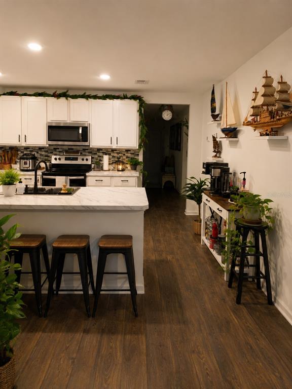 A kitchen with white cabinets, a marble-topped island, bar stools, and a coffee station — 5418 HOLLOW BIRCH DRIVE, JACKSONVILLE, FL