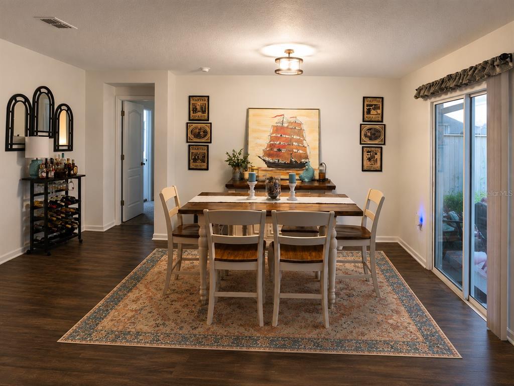 A dining room features a wooden table, six chairs, a rug, and nautical-themed wall art — 5418 HOLLOW BIRCH DRIVE, JACKSONVILLE, FL