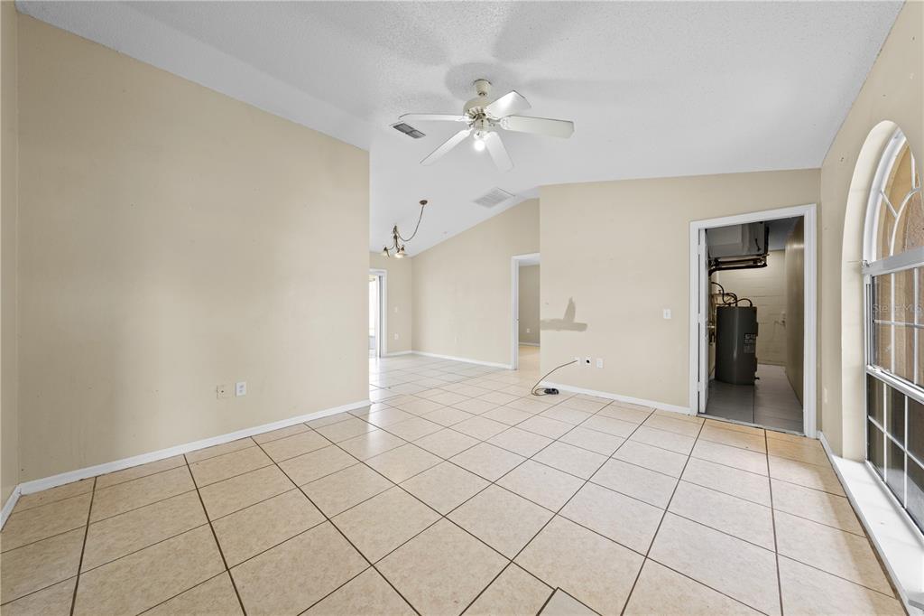An empty room with beige tile flooring, a ceiling fan, and an arched window — 688 JAGUAR COURT, POINCIANA, FL