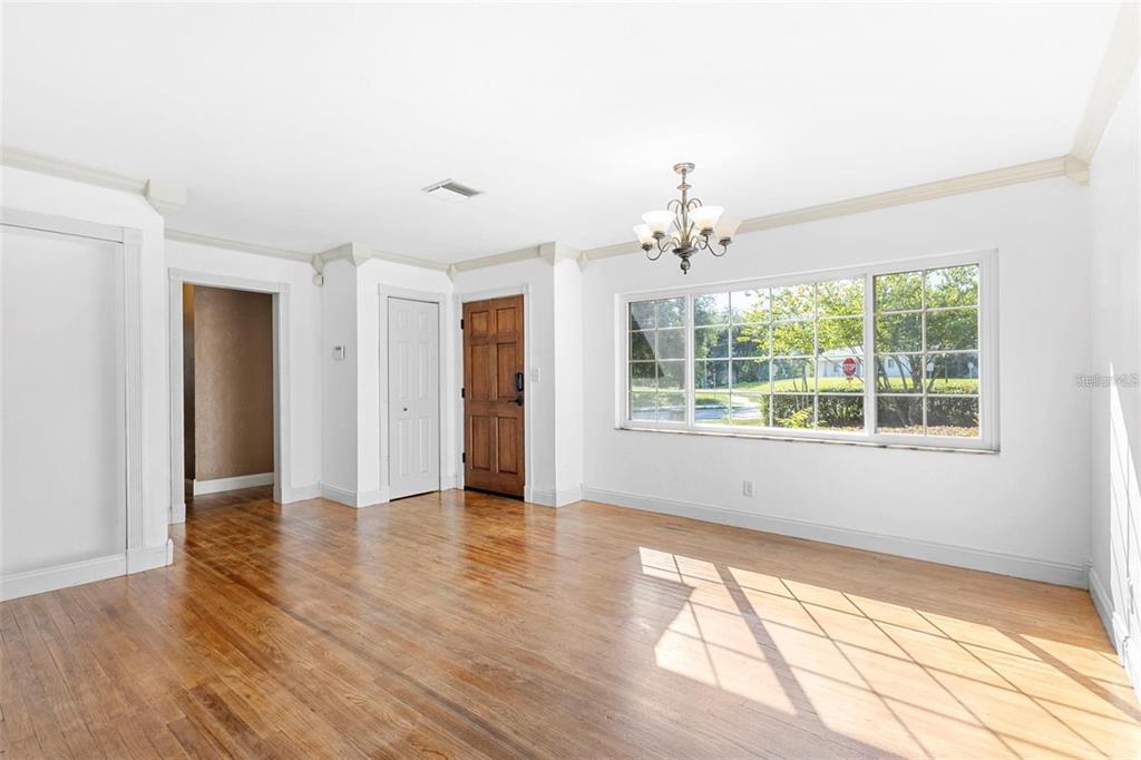 A bright room with hardwood floors, a chandelier, and a wooden front door — 611 N GARFIELD AVENUE, DELAND, FL