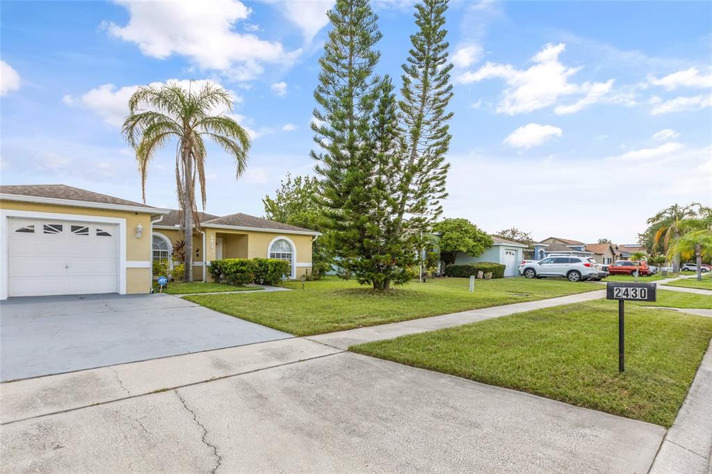 A suburban street view shows a single-story house with a driveway and a front lawn — 2430 QUAIL RUN BOULEVARD, KISSIMMEE, FL