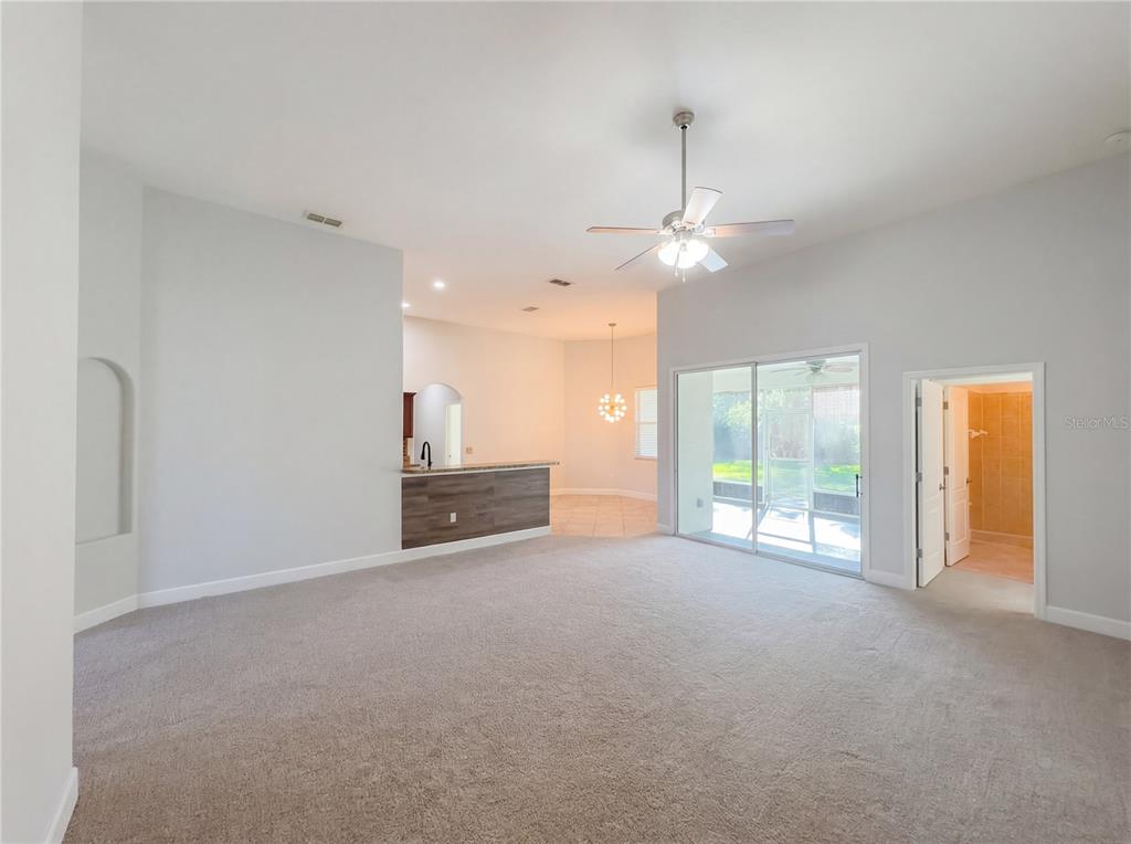A carpeted living room features a ceiling fan, sliding glass doors, and a breakfast bar — 6326 HICKORY LEAF PLACE, LAKELAND, FL