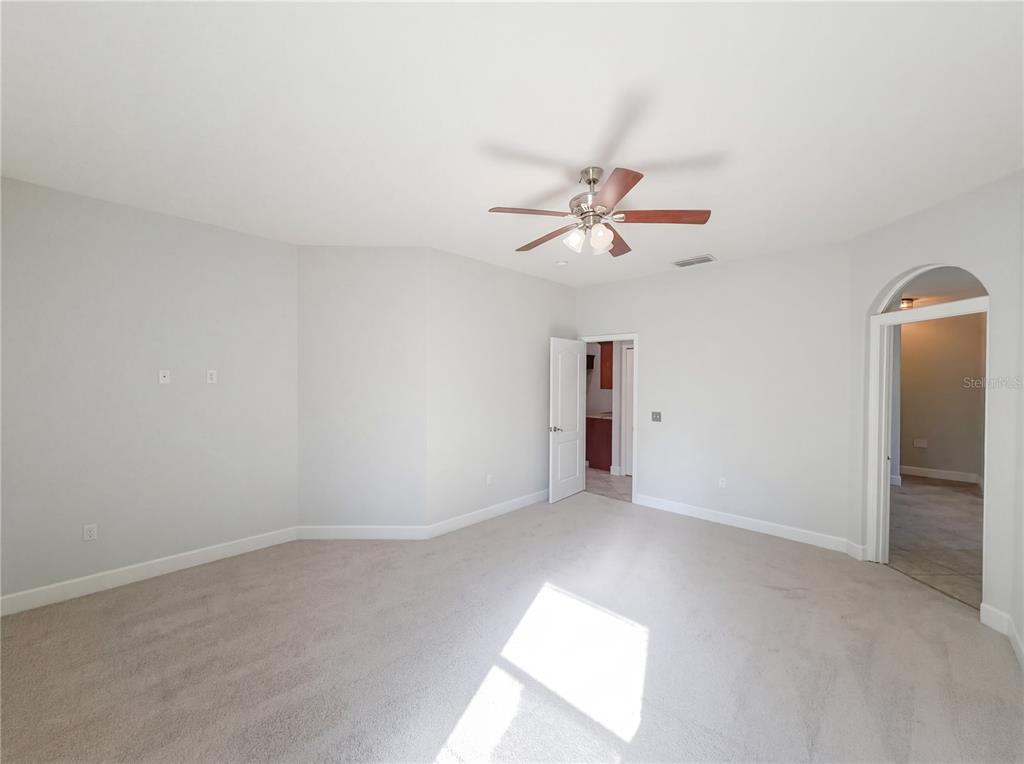 An empty bedroom features light gray walls, beige carpeting, a ceiling fan, and two doorways — 6326 HICKORY LEAF PLACE, LAKELAND, FL
