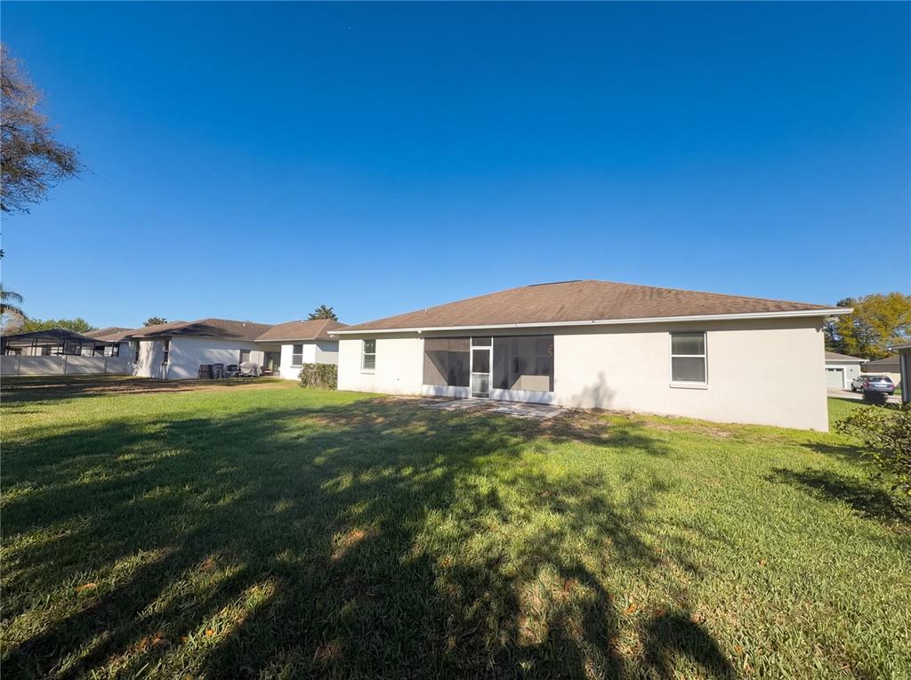 The exterior rear view of a single-story house features a screened-in patio and lawn — 6326 HICKORY LEAF PLACE, LAKELAND, FL