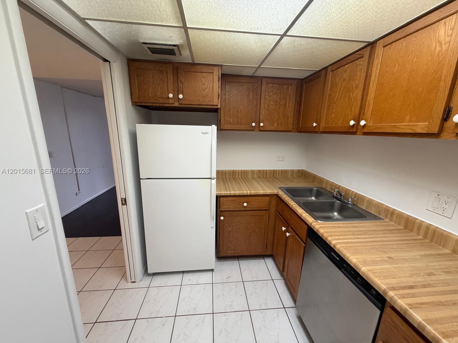 A kitchen features wood cabinets, laminate countertops, a white refrigerator, and a stainless steel dishwasher — 3720 Inverrary Dr # 2K, Lauderhill FL 33319, LAUDERHILL, FL