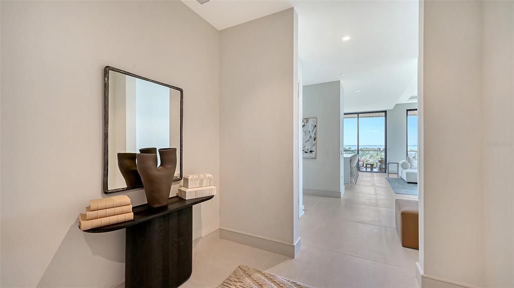 An entryway features a dark console table, a mirror, and a view into a living area — 1591 GULF OF MEXICO DRIVE UNIT 512, LONGBOAT KEY, FL