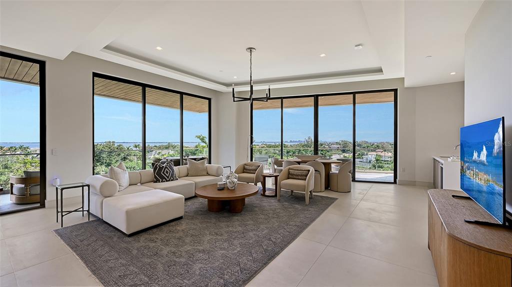 A modern living room features a large sectional sofa, floor-to-ceiling windows, and a scenic view — 1591 GULF OF MEXICO DRIVE UNIT 512, LONGBOAT KEY, FL